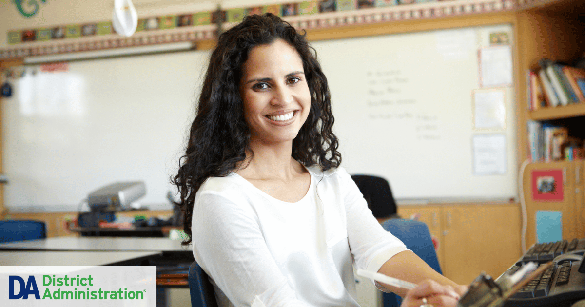 Young teacher in a classroom smiling at the camera