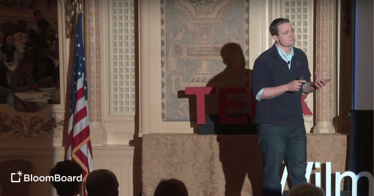 Jason Lange on a stage with TEDX logo behind him.