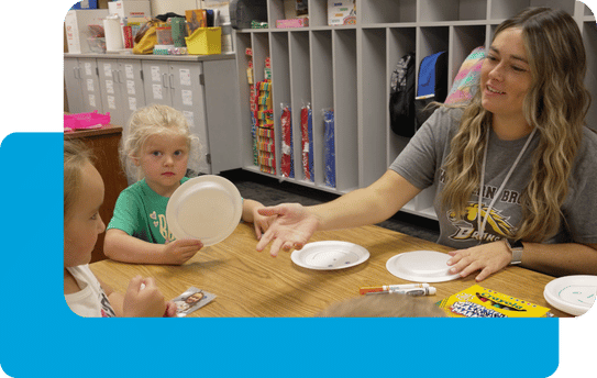 young teacher works with preK students in a classroom.